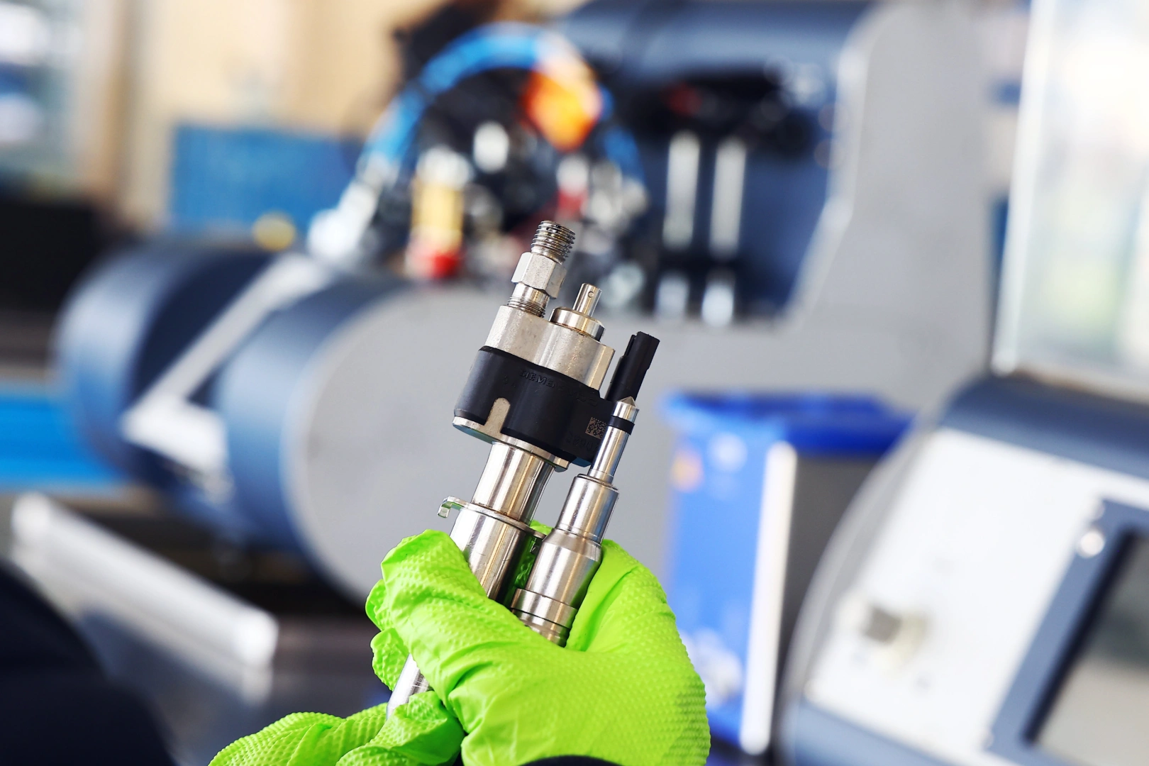 Dwa wtryskiwacze benzynowe trzymane w rękach mechanika na tle specjalistycznego stanowiska diagnostycznego. Dwa wtryskiwacze benzynowe trzymane w rękach mechanika na tle specjalistycznego stanowiska diagnostycznego.