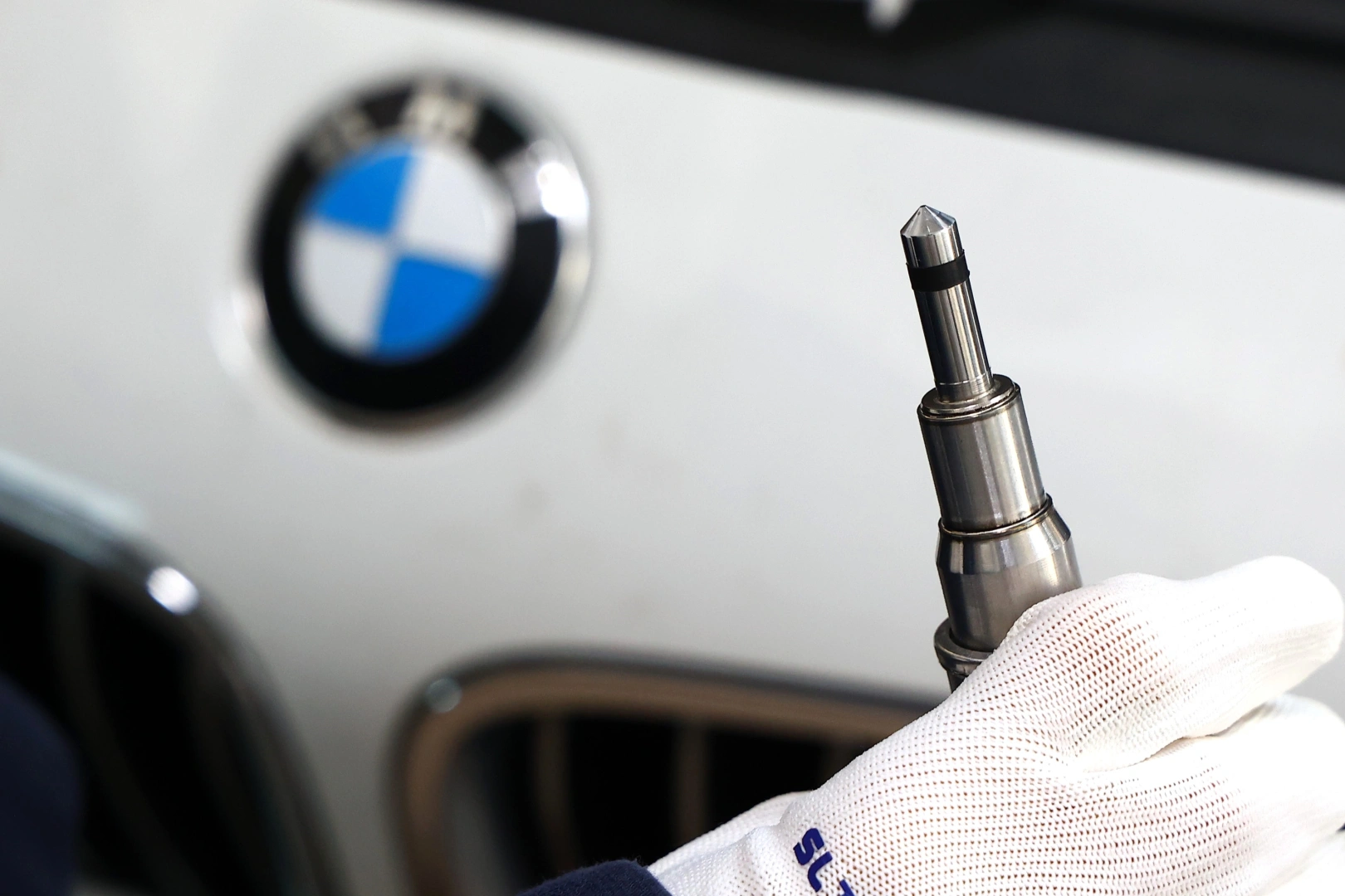 Końcówka wtryskiwacza paliwa na tle samochodu BMW. Końcówka wtryskiwacza paliwa na tle samochodu BMW.
