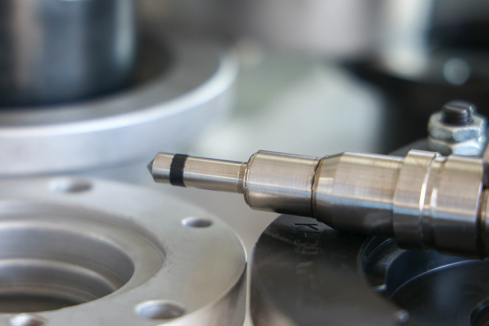 Końcówka wtryskiwacza podczas kontroli technicznej Zbliżenie metalowej końcówki wtryskiwacza umieszczonej przy stanowisku pomiarowym