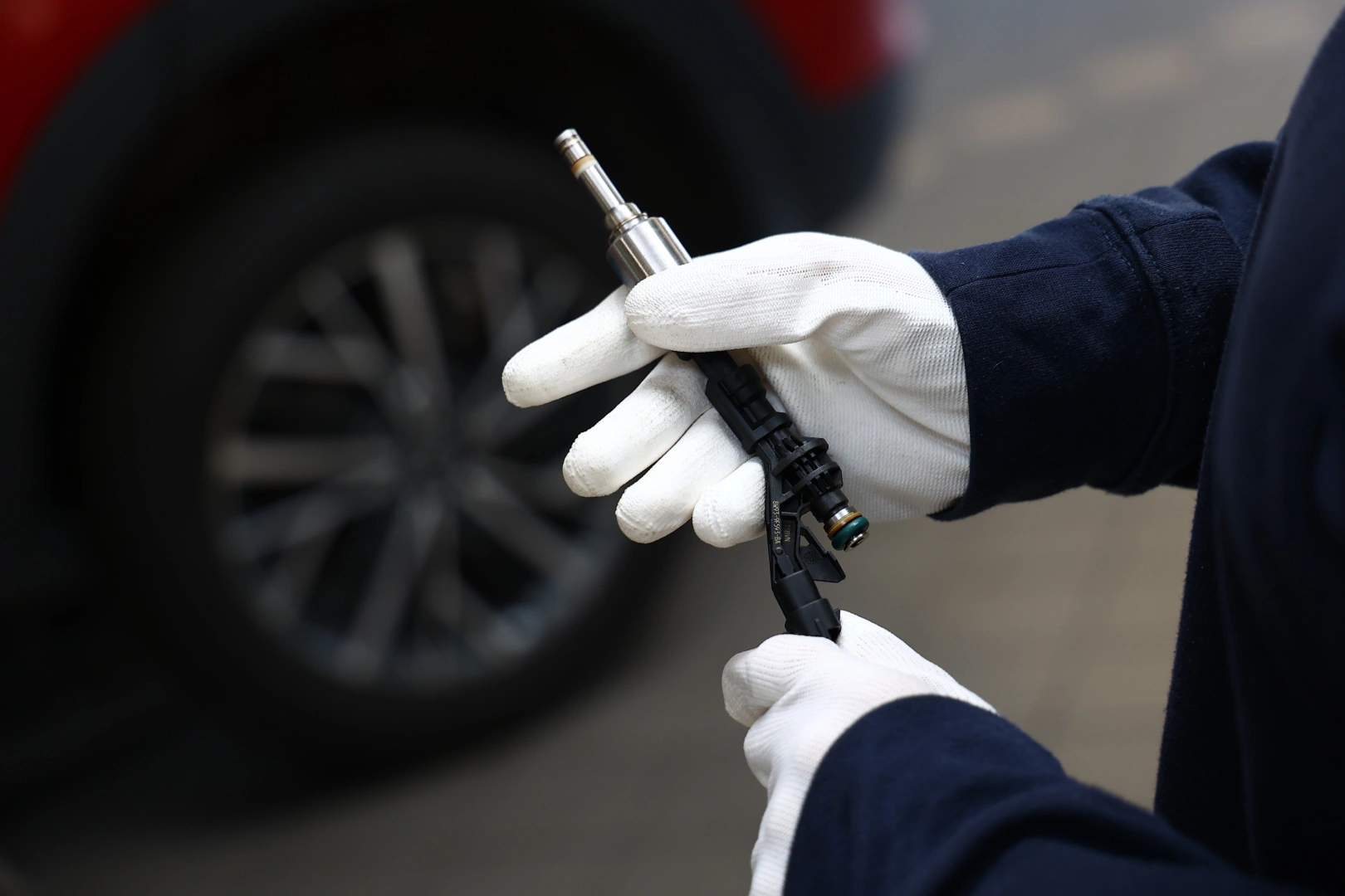 Kontrola wtryskiwacza benzynowego przed diagnostyką Technik trzymający wtryskiwacz benzynowy podczas wstępnej kontroli przed dalszymi testami