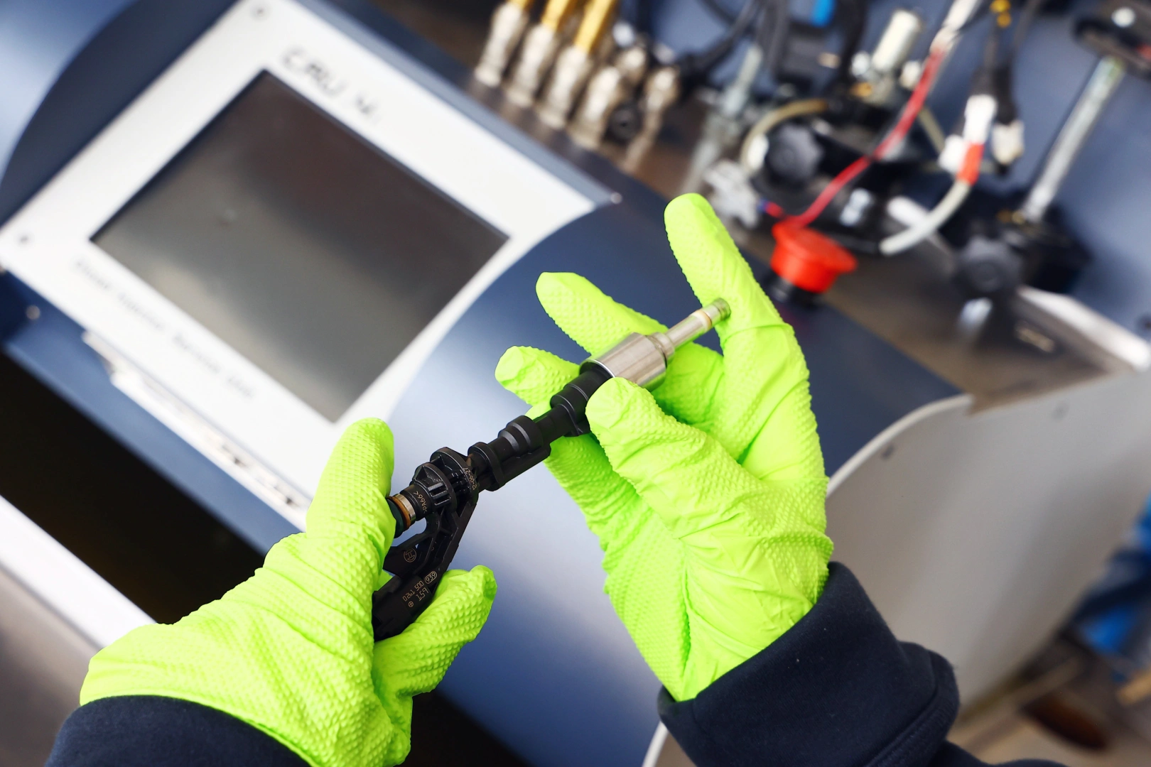 Kontrola wtryskiwacza benzynowego przed testem Technik kontroluje wtryskiwacz benzynowy przed testami na specjalistycznym stanowisku diagnostycznym.