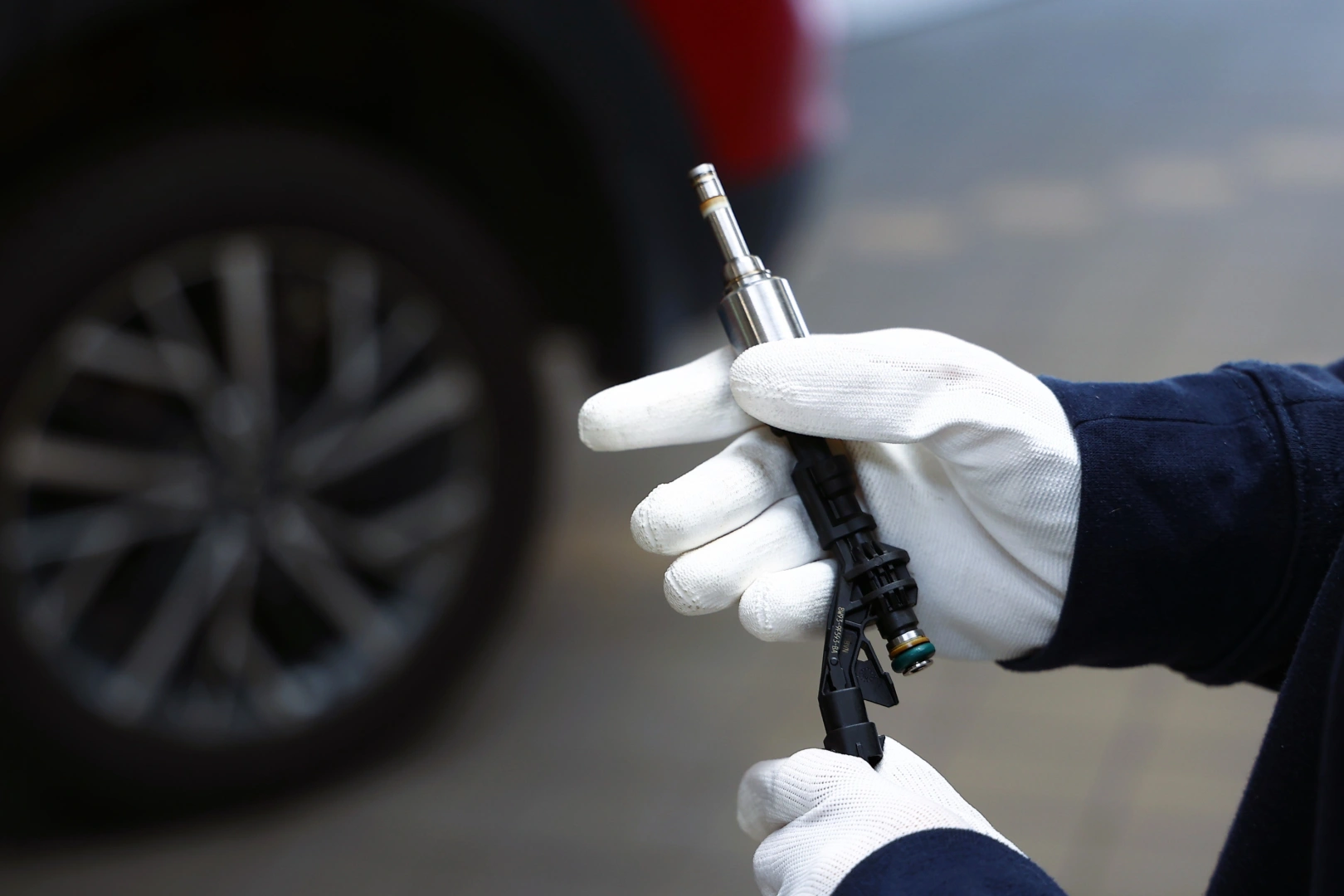 Kontrola wtryskiwacza benzynowego przed testem Technik trzymający wtryskiwacz benzynowy podczas wstępnej kontroli przed diagnostyką stanowiskową