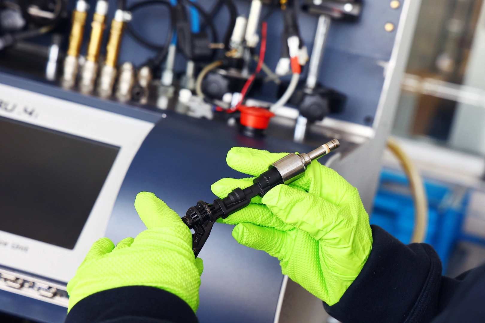 Technik w rękawicach kontrolujący wtryskiwacz benzynowy przed diagnostyką i czyszczeniem