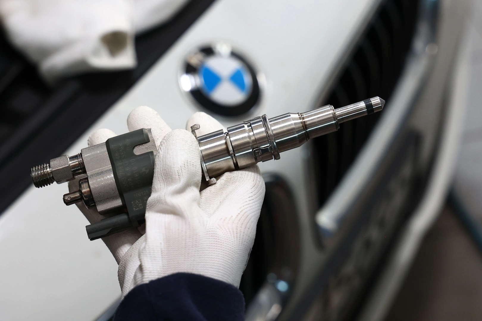 Kontrola wtryskiwacza paliwa przed montażem w pojeździe Technik trzymający wtryskiwacz paliwa przed montażem w samochodzie BMW