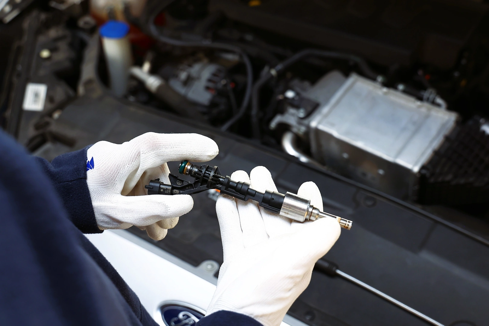 Mechanik ocenia wtryskiwacz benzynowy przed montażem w układzie paliwowym samochodu Mechanik ocenia wtryskiwacz benzynowy przed montażem w układzie paliwowym samochodu