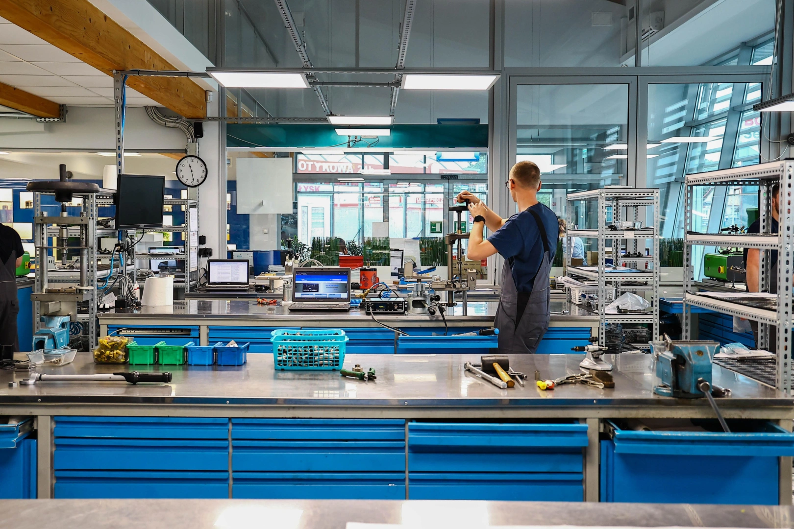 Technik pracujący przy wyposażonym stanowisku warsztatowym z urządzeniami pomiarowymi i narzędziami