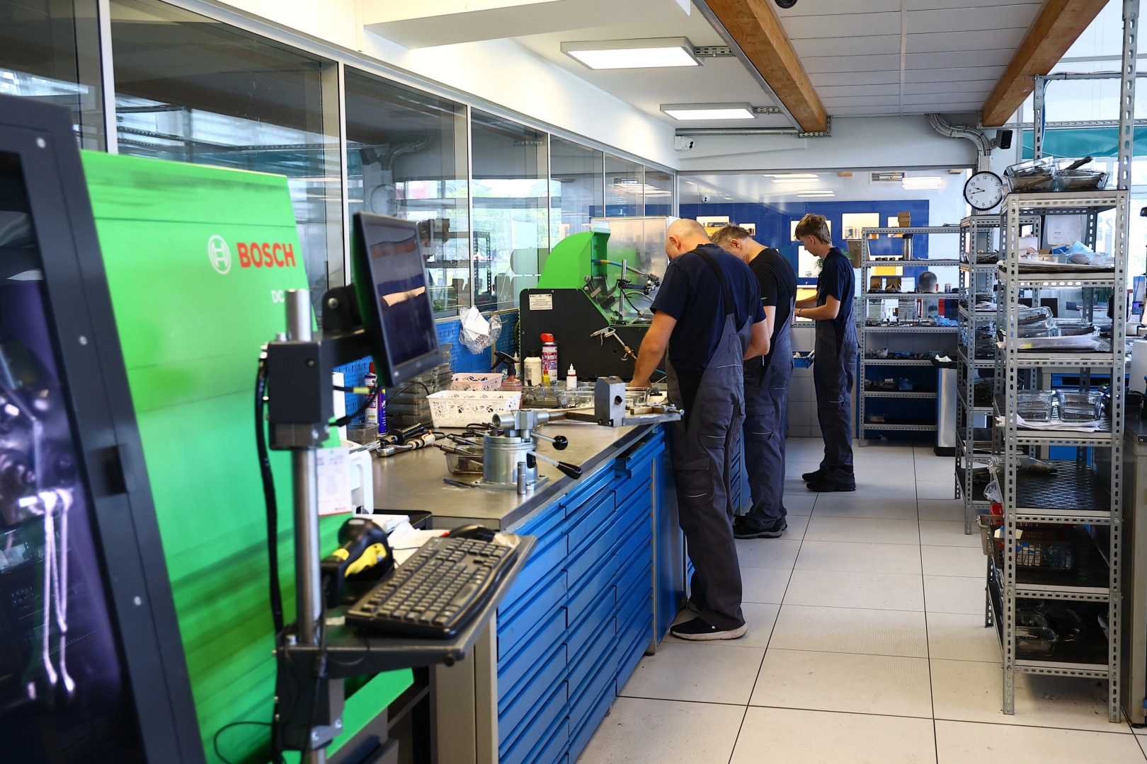 Praca techników w specjalistycznej pracowni regeneracji wtryskiwaczy Technicy pracujący przy stanowiskach Bosch w pracowni regeneracji wtryskiwaczy