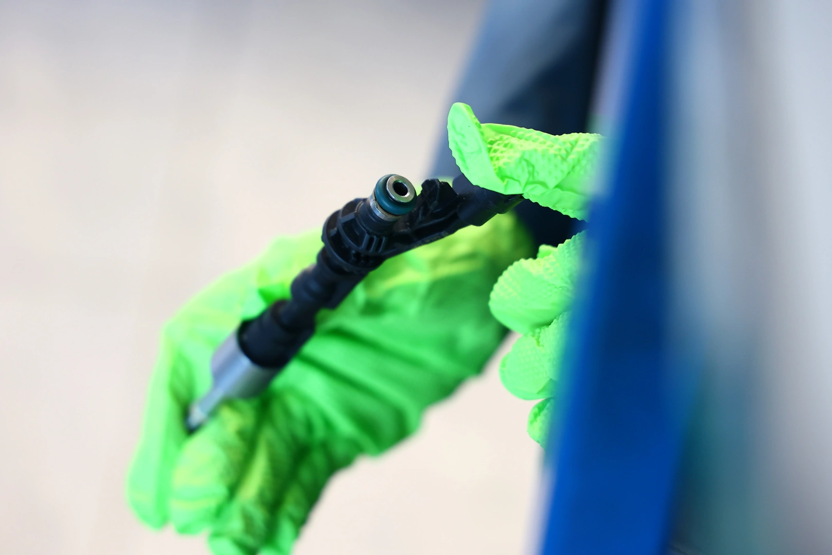 Precyzyjne prace serwisowe i techniczne Technik w zielonych rękawiczkach wykonujący precyzyjne prace serwisowe przy elemencie technicznym.