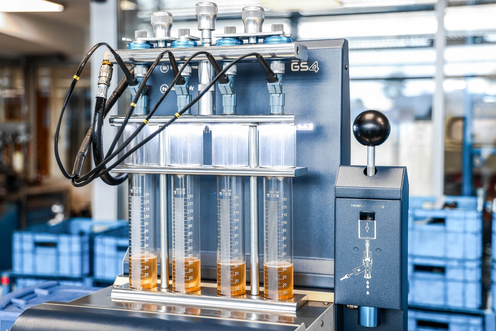 Stanowisko do pomiaru wydajności wtryskiwaczy z czterema cylindrami pomiarowymi wypełnionymi cieczą testową. Stanowisko do pomiaru wydajności wtryskiwaczy z czterema cylindrami pomiarowymi wypełnionymi cieczą testową.
