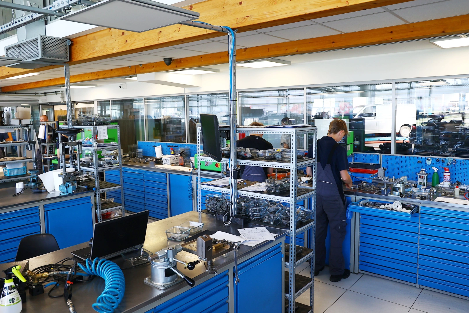 Technicy pracujący przy stanowiskach roboczych w nowoczesnej pracowni wtryskiwaczy benzynowych. Technicy pracujący przy stanowiskach roboczych w nowoczesnej pracowni wtryskiwaczy benzynowych.