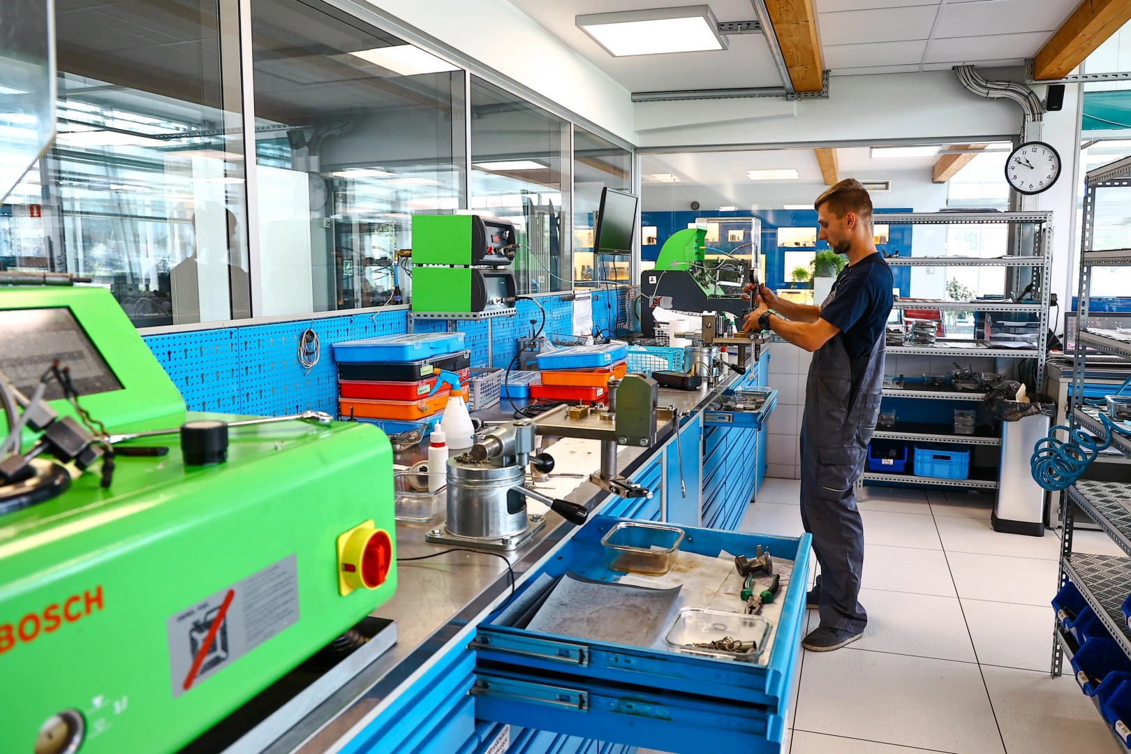 Technik podczas przygotowania wtryskiwacza do testu Technik pracujący przy stanowisku serwisowym podczas przygotowania wtryskiwacza do dalszej diagnostyki