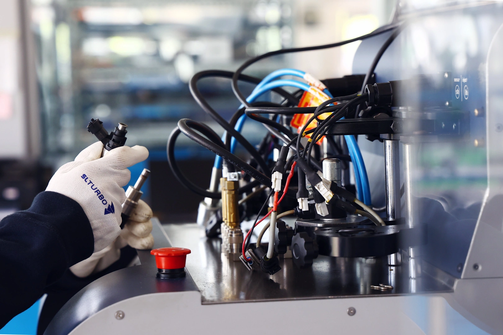 Technik przygotowuje wtryskiwacz benzynowy do testu na specjalistycznym stanowisku probierczym. Technik przygotowuje wtryskiwacz benzynowy do testu na specjalistycznym stanowisku probierczym.