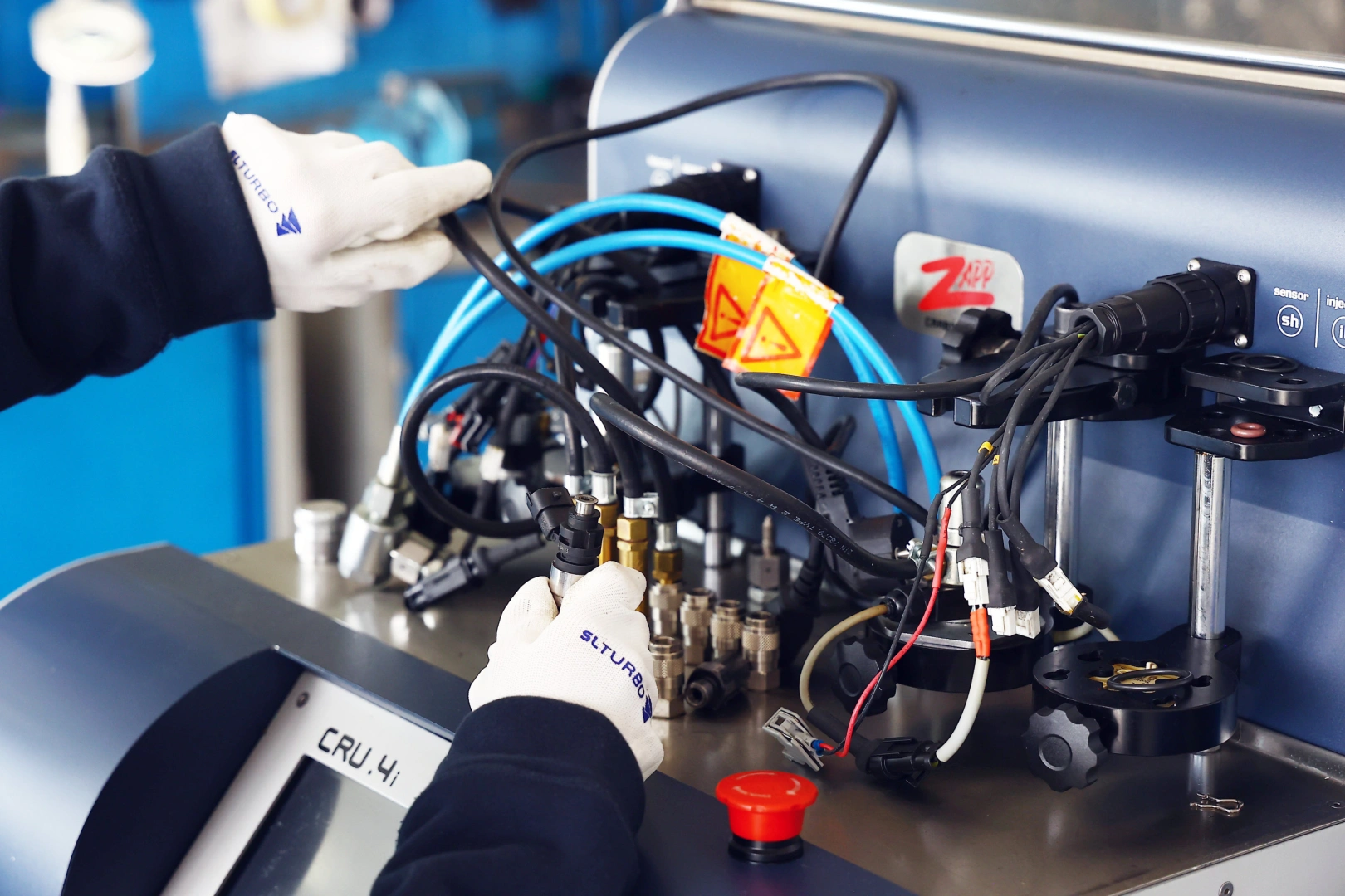 Technik przygotowuje wtryskiwacz benzynowy do testów na stanowisku Carbon Zapp, podłączając przewody sterujące i układ pomiarowy przed diagnostyką parametrów pracy Technik przygotowuje wtryskiwacz benzynowy do testów na stanowisku Carbon Zapp, podłączając przewody sterujące i układ pomiarowy przed diagnostyką parametrów pracy