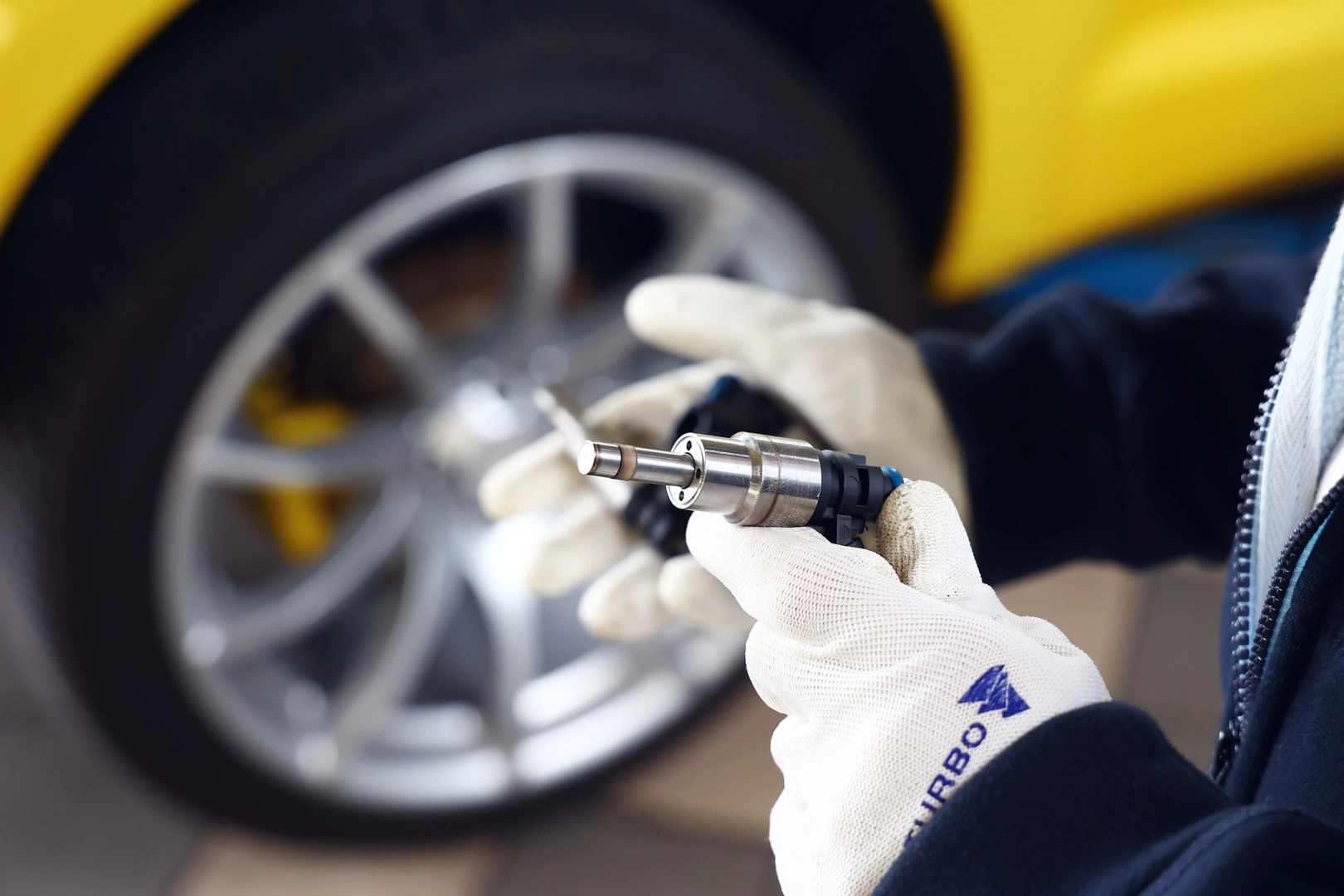 Technik trzyma wtryskiwacz benzynowy podczas oględzin jego korpusu, końcówki i przyłącza przed dalszym testowaniem. Technik trzyma wtryskiwacz benzynowy podczas oględzin jego korpusu, końcówki i przyłącza przed dalszym testowaniem.