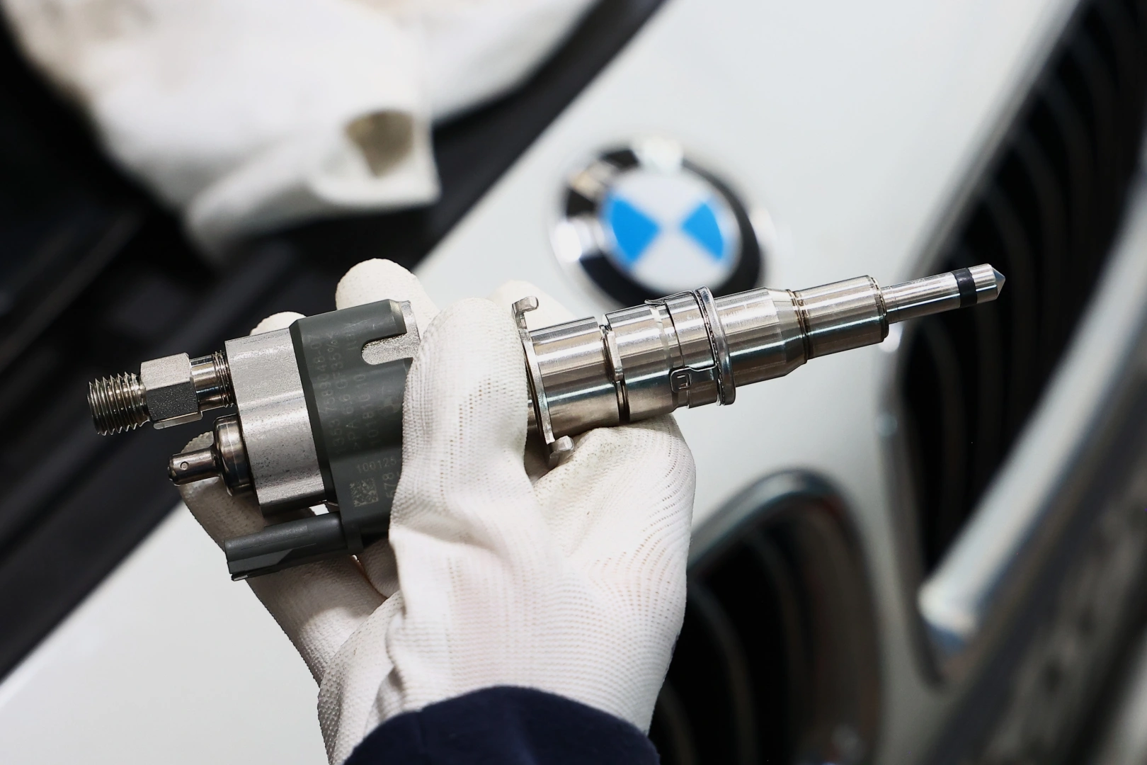 Technik trzyma wtryskiwacz paliwa podczas serwisu samochodu Technik trzyma wtryskiwacz paliwa podczas serwisu samochodu