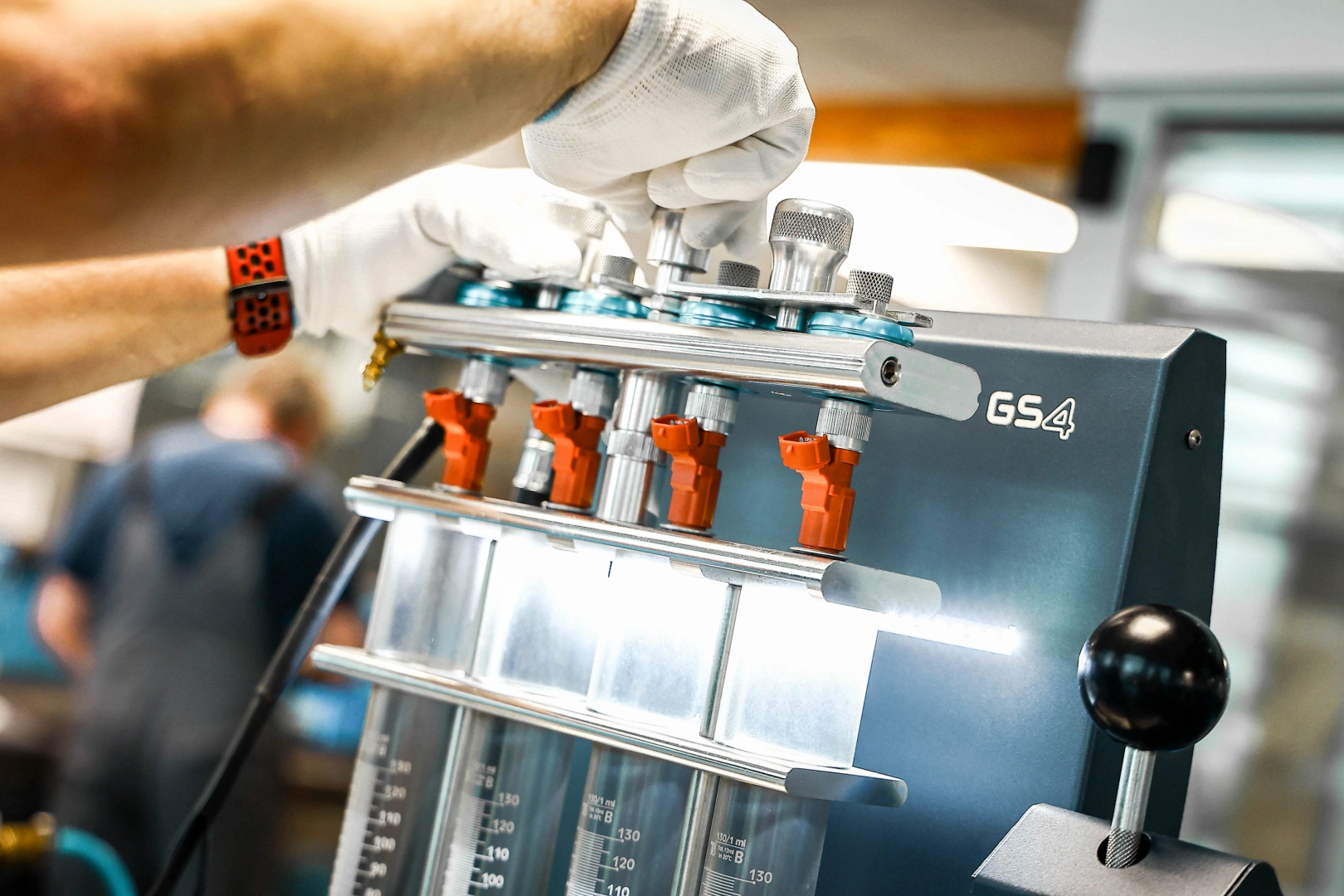 Technik wykonuje diagnostykę wtryskiwaczy benzynowych na stanowisku testowym. Technik wykonuje diagnostykę wtryskiwaczy benzynowych na stanowisku testowym.