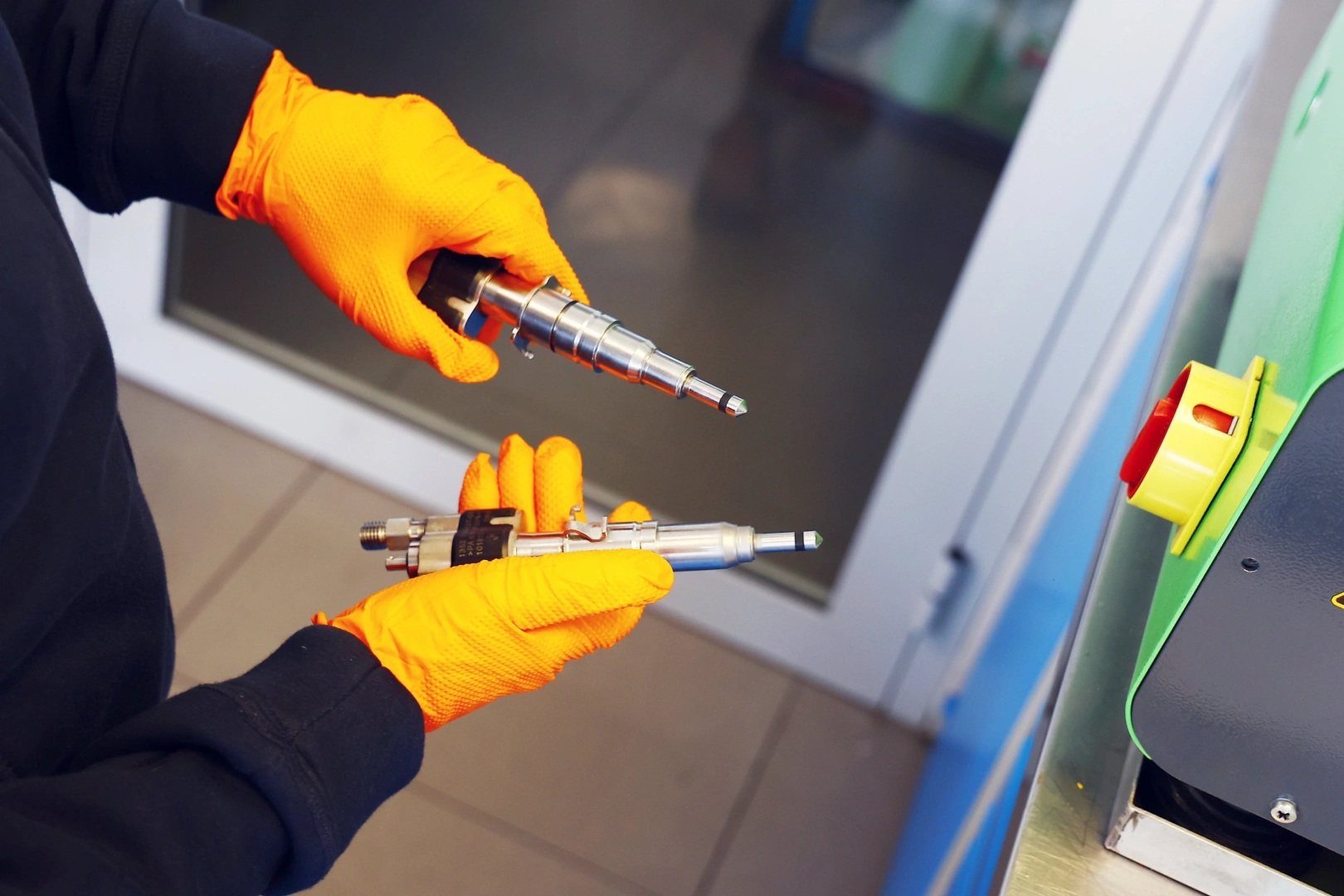 Testowanie i regeneracja wtryskiwaczy benzynowych Technik prezentujący dwa wtryskiwacze benzynowe przed testowaniem na stanowisku serwisowym