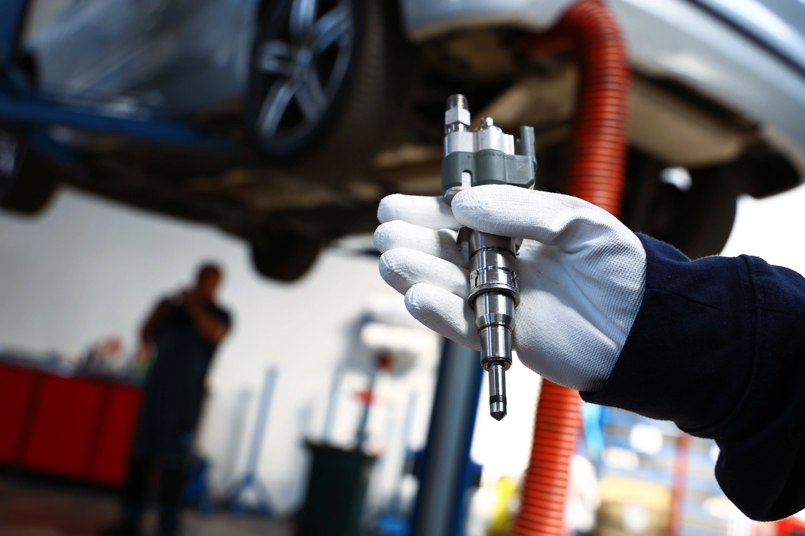 Wtryskiwacz benzynowy Siemens VDO trzymany przez pracownika podczas kontroli przed montażem w samochodzie. Wtryskiwacz benzynowy Siemens VDO trzymany przez pracownika podczas kontroli przed montażem w samochodzie.