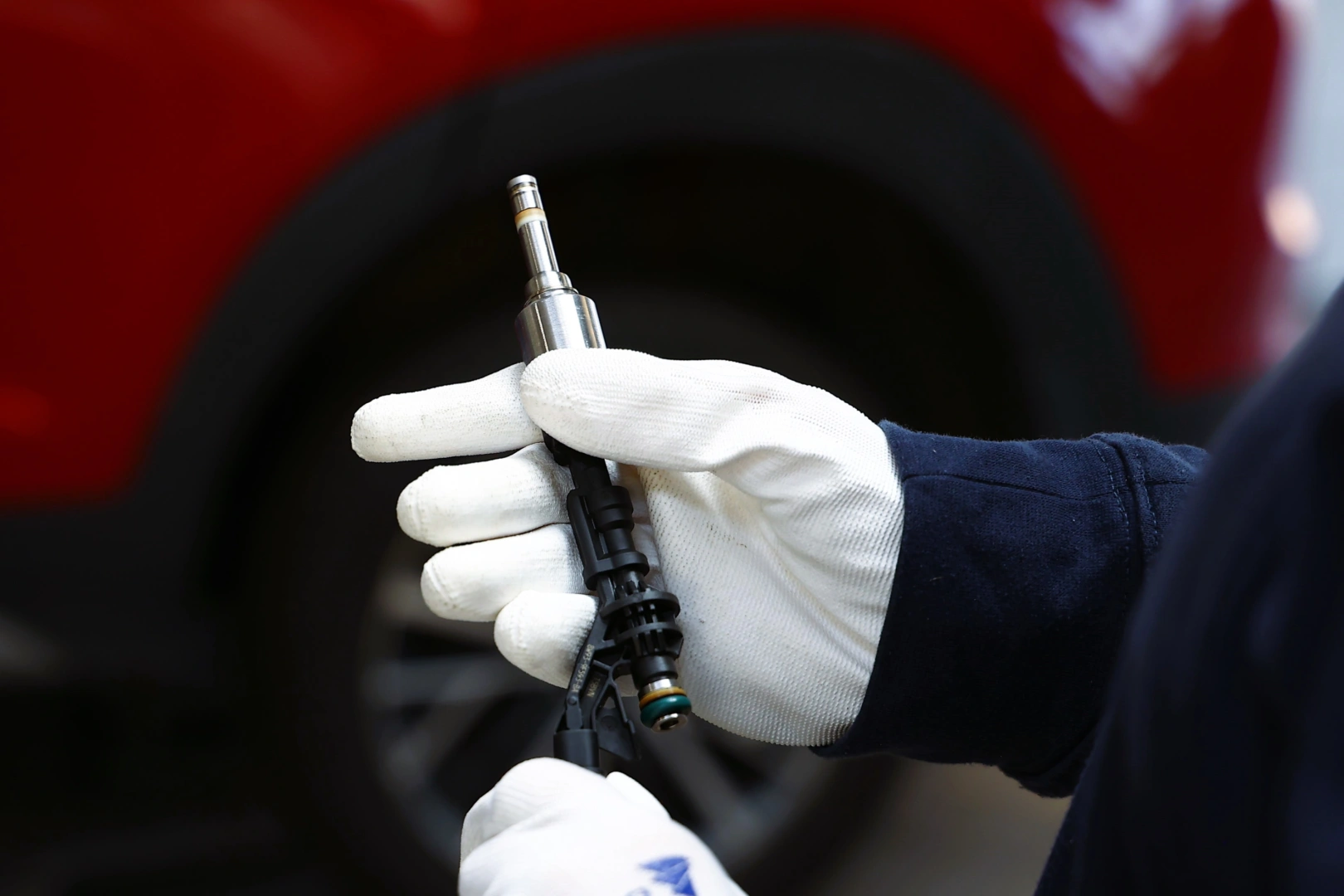 Wtryskiwacz benzynowy podczas kontroli technicznej Technik trzymający wtryskiwacz benzynowy podczas oględzin przed dalszą diagnostyką