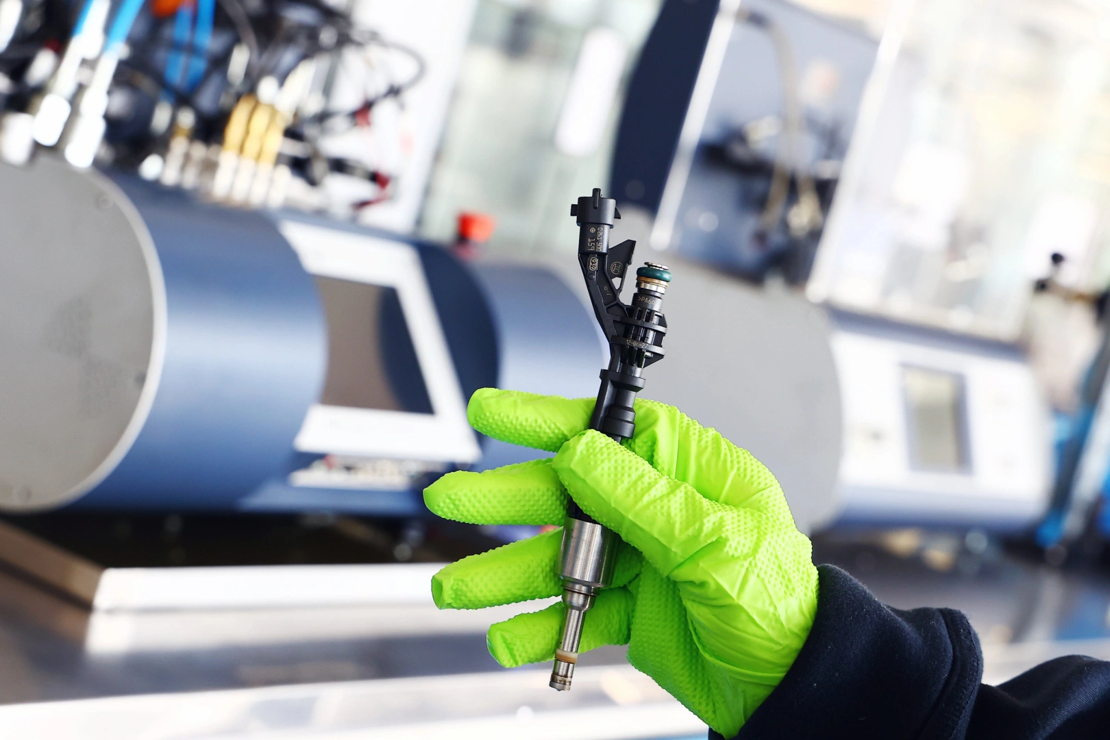 Wtryskiwacz benzynowy przygotowany do diagnostyki stanowiskowej Wtryskiwacz benzynowy trzymany w rękawicy przed wykonaniem testu szczelności, dawkowania i rozpylania