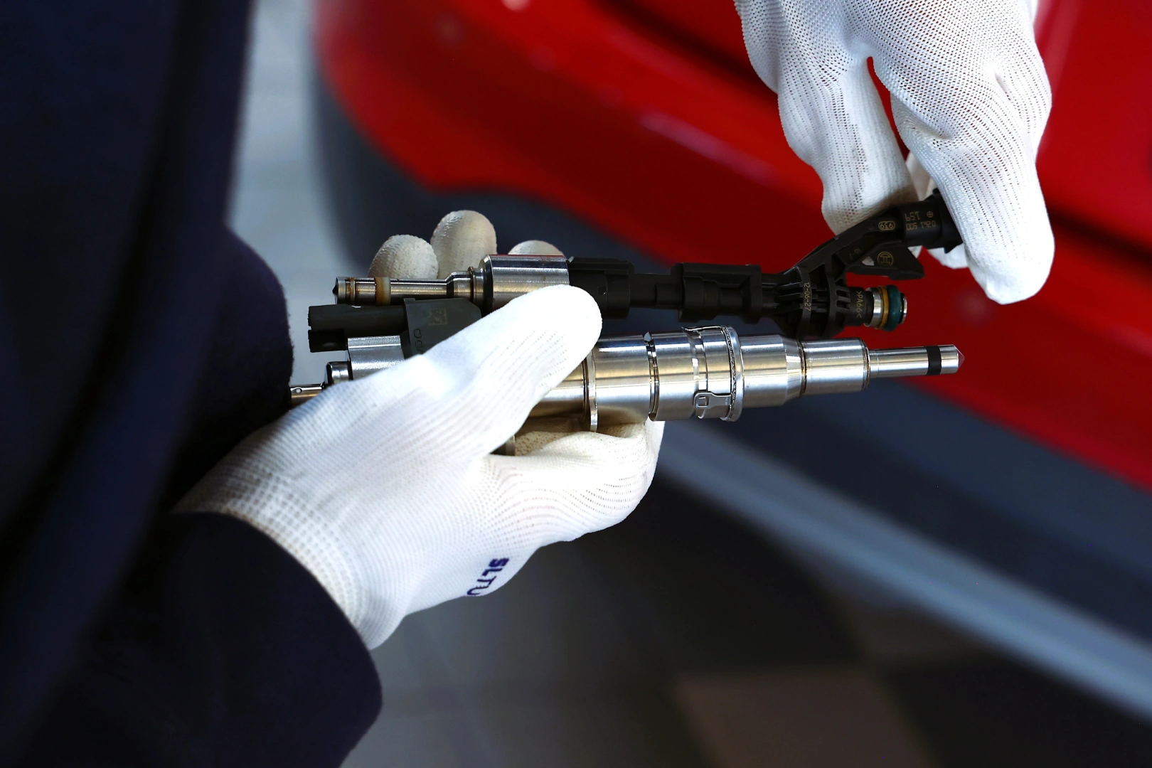 Wtryskiwacze podczas kontroli przed dalszą diagnostyką Dwa wtryskiwacze trzymane w białych rękawicach podczas porównania konstrukcji i przygotowania do testów